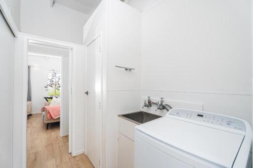 a white kitchen with a sink and a washing machine at Beachside on Hinemoa in Whangamata