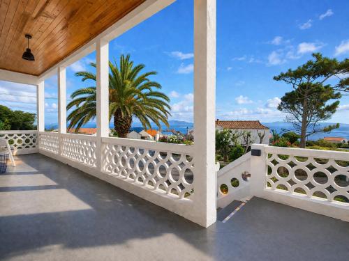 an outdoor balcony with a white fence and a palm tree at Inn Fraga in Ribeirinha