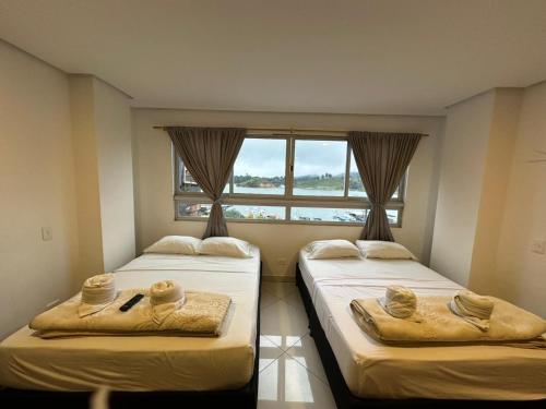 two beds in a room with a window at Hotel Bahia Guatape in Guatapé