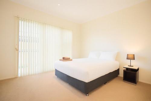 a bedroom with a white bed and a window at Modern 2BR Townhouse with BBQ & Pool Access in Muswellbrook