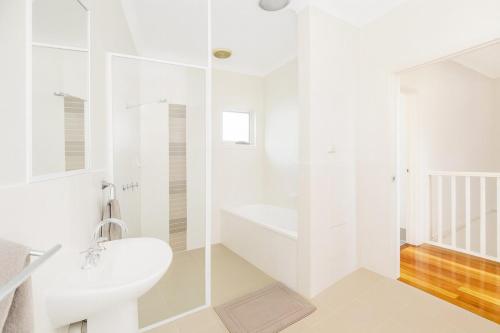 a white bathroom with a toilet and a sink at Modern 2BR Townhouse with BBQ & Pool Access in Muswellbrook