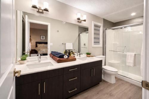 a bathroom with a sink and a shower and a toilet at NorthEdge Suites Leduc in Leduc