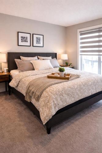 a bedroom with a large bed with a tray on it at NorthEdge Suites Leduc in Leduc
