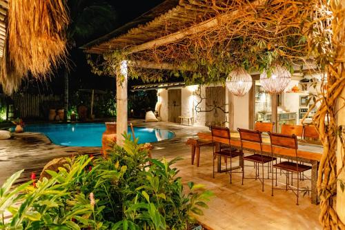 a resort with a pool and a table and chairs at Villa Fulô in Caraíva