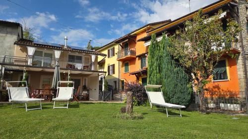 a yard with two white chairs in front of a house at Lùlù Guest House in Dernice