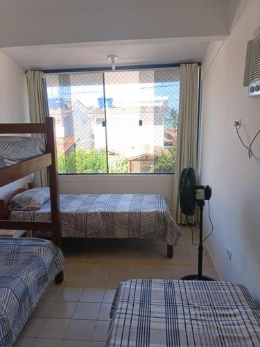 a bedroom with two beds and a large window at Bonito Itapuama Beach in Cabo de Santo Agostinho