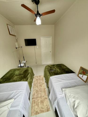 a bedroom with two beds and a ceiling fan at Angra Prime Centro in Angra dos Reis