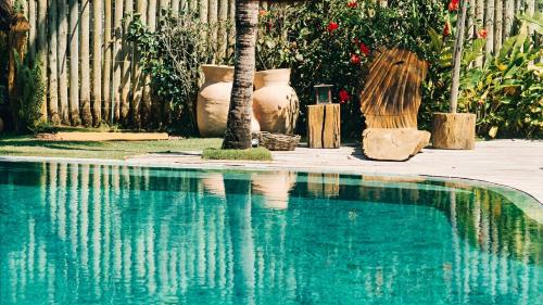 a blue swimming pool with vases and a palm tree at Villa Fulô in Caraíva