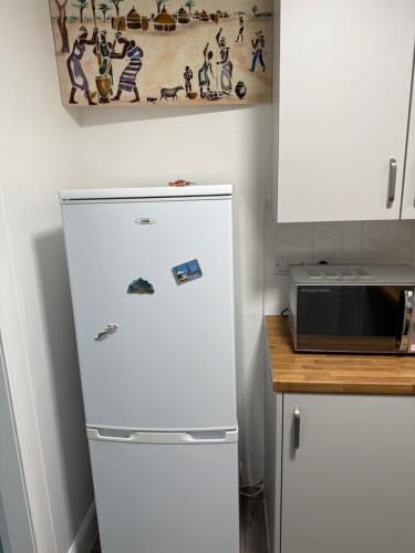 a white refrigerator in a kitchen next to a counter at Zikach Apartment Near to Glasgow Airport in Renfrew