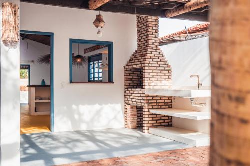 a brick fireplace in a room with a sink at Casa Pema - Grupo Casa Camurupim in Barra Grande
