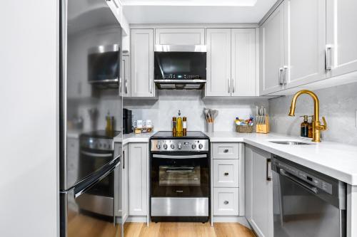 a kitchen with white cabinets and a stove top oven at The McCaul by Casa Hotels Near AGO Basement Suite in Toronto