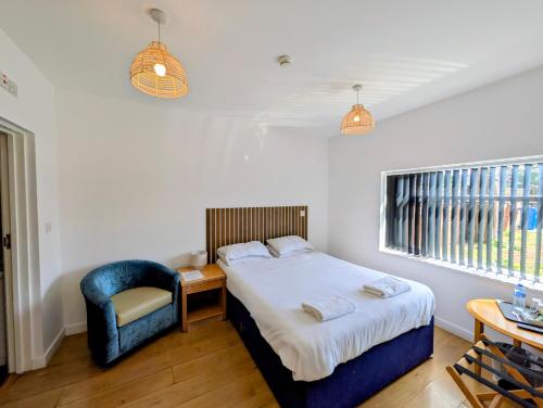 a bedroom with a bed and a blue chair at Oscar Lodge in Northampton