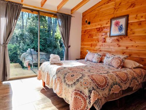 a bedroom with a bed in front of a window at Cabañas Lagos y Volcanes in Coñaripe