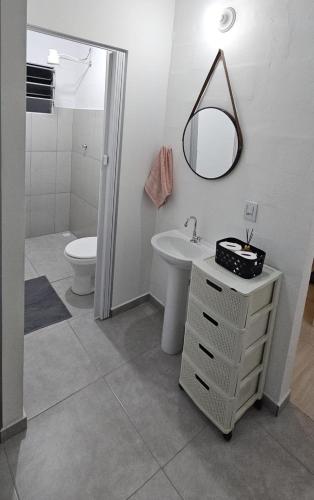 a bathroom with a sink and a toilet and a mirror at Casa Completa em Cotia com estacionamento in Cotia