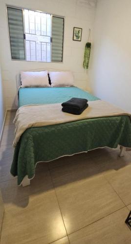 a bedroom with a bed with a green blanket on it at Casa Completa em Cotia com estacionamento in Cotia
