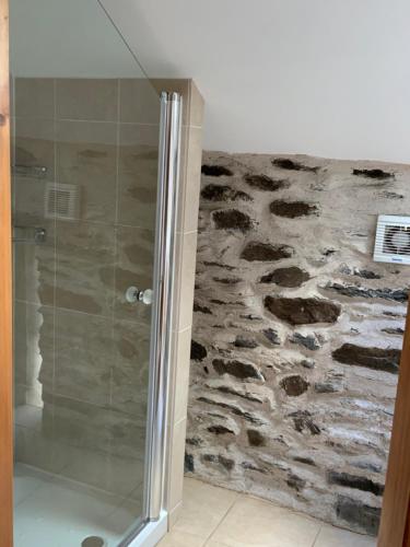 a shower in a bathroom with a stone wall at Tithe Barn 1 - Abercelyn Cottages - Llanycil - Bala - Gwynedd - LL23 7YF - UK in Llanycil