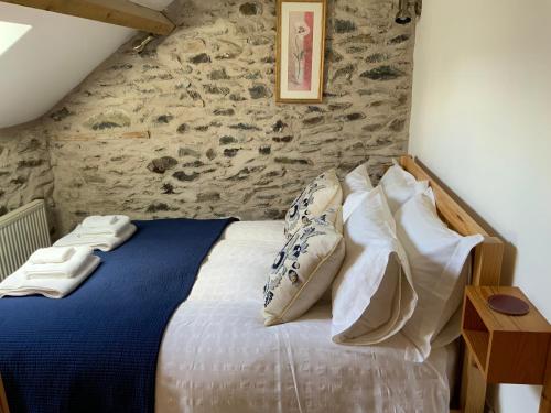 a bedroom with a bed with pillows and a stone wall at Tithe Barn 1 - Abercelyn Cottages - Llanycil - Bala - Gwynedd - LL23 7YF - UK in Llanycil