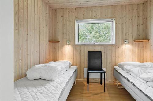 a bedroom with two beds and a chair and a window at 30460-Odder-Strandvaenget-16 in Odder