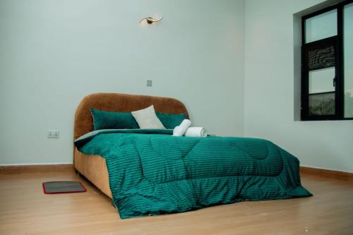 a bed with a green blanket and a chair at Ham Homes in Kampala