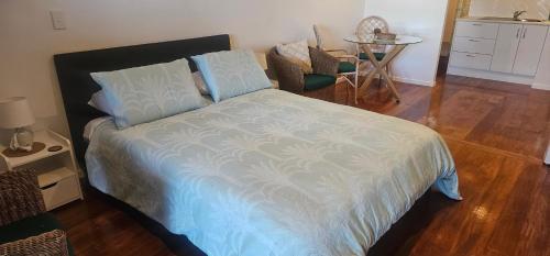 a bedroom with a bed and a table and a chair at Mansio Awatere in Snells Beach