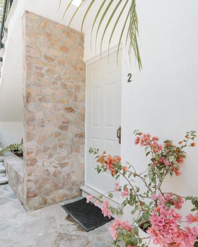 a white door with flowers next to a stone wall at Casa de Lago in Jalpan de Serra
