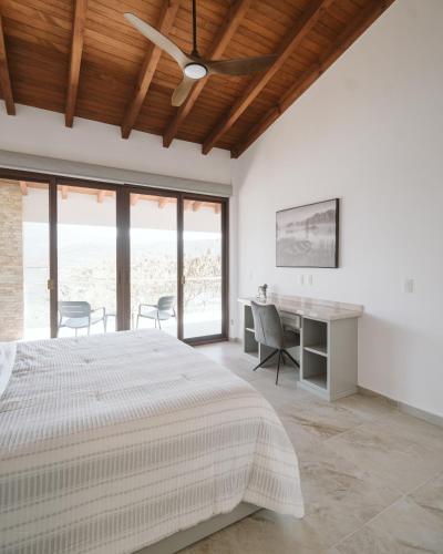 a bedroom with a bed and a desk and windows at Casa de Lago in Jalpan de Serra