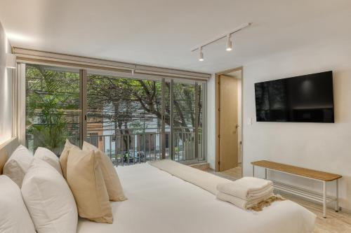 a large white bed in a room with a large window at Casa Hugo by Capitalia in Mexico City