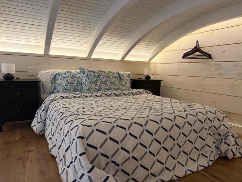 a bedroom with a bed with a white and black comforter at Backyard Tiny House in the Woods in Tolland