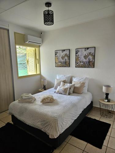 a bedroom with a bed with white sheets and pillows at Villa dix blue in Kourou