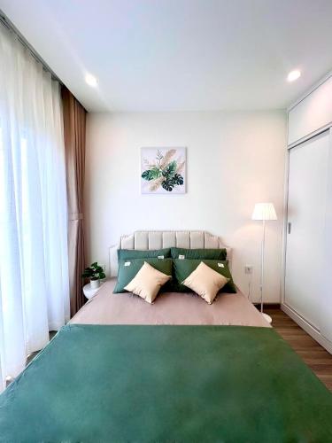 a bedroom with a large bed with a green blanket at MH Home in Long Bình