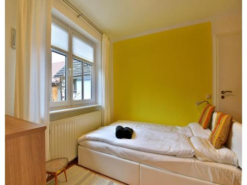 a room with a bed with a yellow wall and a window at Ferienwohnung im Erholungsort Suhl in Suhl