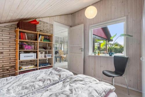 a bedroom with a bed and a chair and a window at 30073-Ulfborg-Grastensborgvej-35 in Ulfborg