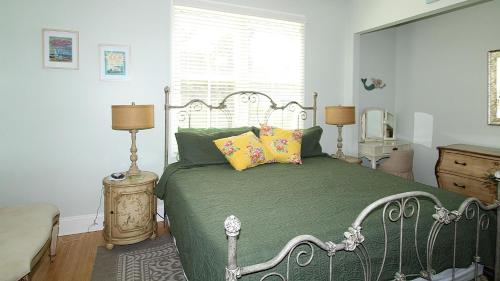 a bedroom with a bed with green sheets and pillows at Breezes On Broad in Cape May