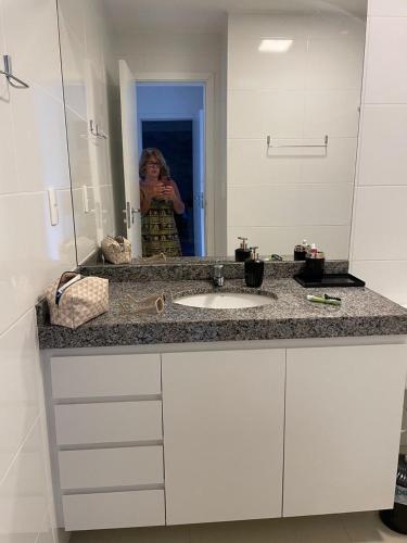 a woman taking a picture of a bathroom sink at Garden em Guarajuba in Tareco