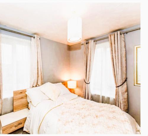 a bedroom with a bed and two windows at Elegant 2 BR Apartment in Historic Cambridge in Papworth Everard