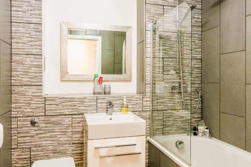a bathroom with a sink and a mirror and a tub at Elegant 2 BR Apartment in Historic Cambridge in Papworth Everard