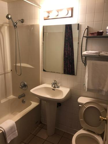 a bathroom with a sink and a toilet and a mirror at HWY Express Inn & Suites in Stillwater