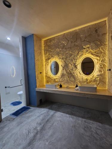a bathroom with two sinks and a stone wall at Casa Laura Penthouse in El Cuyo