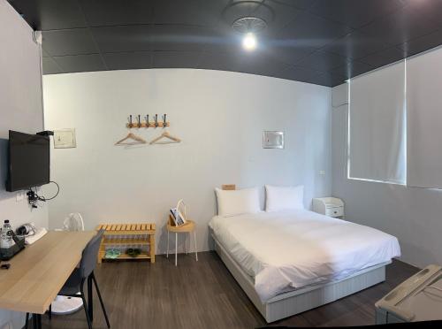 a bedroom with a white bed and a desk at 好客輕旅 in Donggang