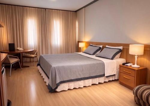 a hotel room with a large bed and a desk at Terrazzo Hotel Campos dos Goytacazes in Campos dos Goytacazes