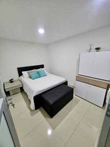a white bedroom with a bed and a stool at Raíz Serena in El Retiro