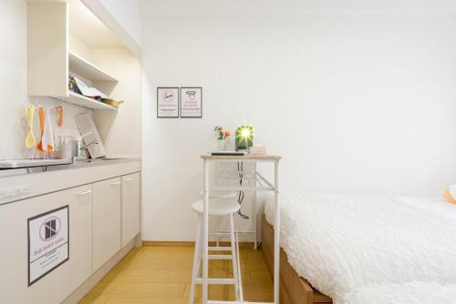 a small kitchen with a bed and a stool in a room at アンドステイ屋形町306 in Kyoto