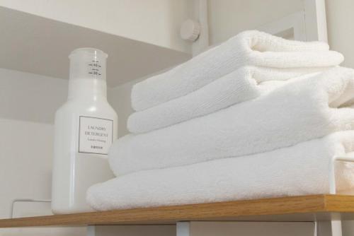 a stack of towels on a shelf with a bottle of soap at アンドステイ屋形町306 in Kyoto