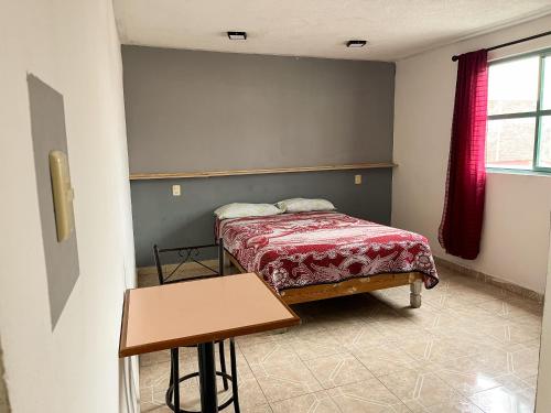 a small bedroom with a bed and a table at Real Hotel y Alojamientos in Pachuca de Soto