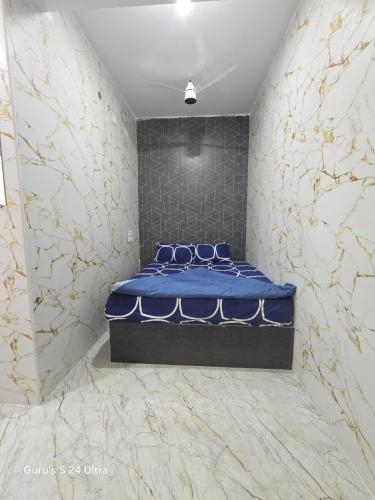 a bedroom with a blue bed in a room with marble walls at Sree Guru Sannidhi in Jāmb