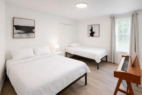 a white bedroom with two beds and a piano at Mohegan Sun Getaway Large Group Retreat in Danielson