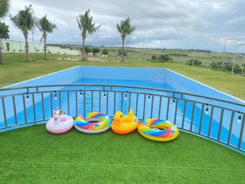 a row of colorful inflatableoses sitting next to a pool at Bàu Trắng Garden in Ấp Nhơn Hòa
