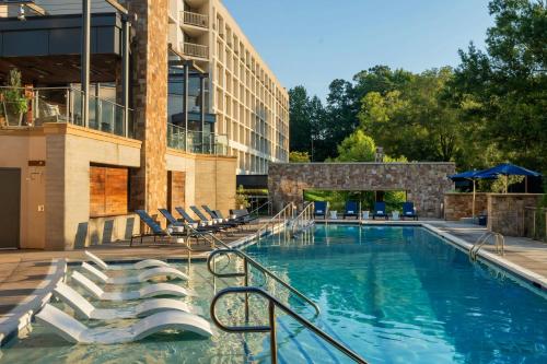 a swimming pool with chairs and a building at Raleigh Marriott Crabtree Valley in Raleigh