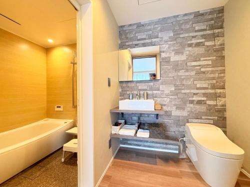 a bathroom with a white toilet and a stone wall at The Lobs Five, Brand New, 4 bedroom, 3 bath, 4 toilet, 8 min to Rusutsu, 7-11, bus at door in Kimobetsu