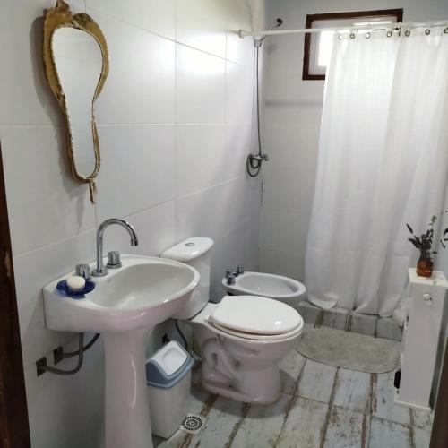 a white bathroom with a toilet and a sink at Entre Tanto in Luyaba